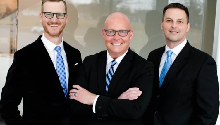Dr. Brenton Koch, Dr. Cody Koch, and Dr. Michael Carlisle smiling in suits
