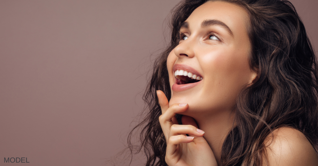 Woman with clear skin looking up and smiling (model)