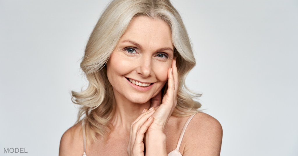 Older woman touching her face and smiling (model)